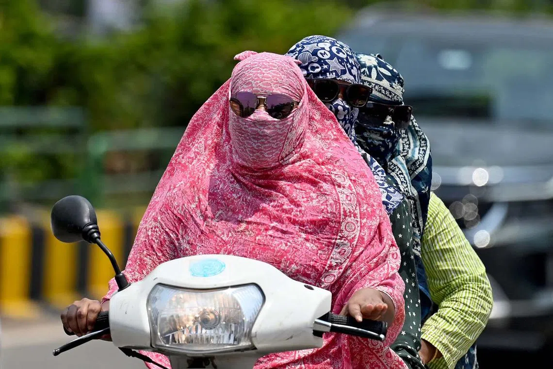 Women with their faces covered while riding a two-wheeler on a hot day, in Raipur, India, on April 15, 2024.