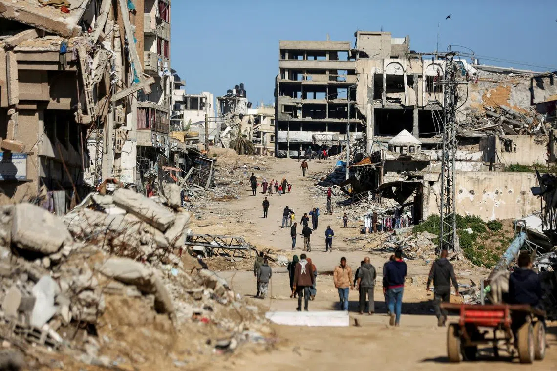 FILE PHOTO: Palestinians walk past the ruins of houses destroyed during Israel's military offensive, amid the ongoing conflict between Israel and Hamas, in Gaza City, March 20, 2024. REUTERS/Dawoud Abu Alkas/File Photo