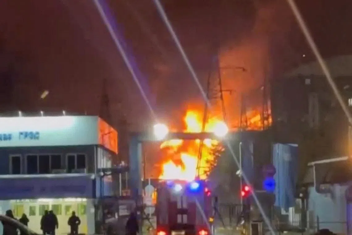 A person stands by an emergency vehicle as fire and smoke rise around the Shatura Power Station in Shatura, Russia, after Ukrainian drones struck the facility early Sunday, Moscow region governor Andrei Vorobyov said, in this still image taken from a social media video released November November 23, 2025. SOCIAL MEDIA/via REUTERS