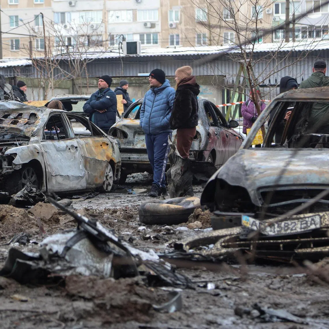 Residents standing next to burned cars at the site of an overnight Russian drone and missile attack on the Ukrainian city of Zaporizhzhia, on Jan 28.
