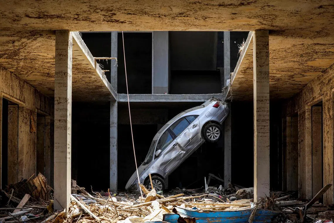 A tilted car sitting above debris in Libya's eastern city of Derna on Sept 18, following deadly flash floods. A week after a tsunami-sized flash flood devastated the Libyan coastal city of Derna, sweeping thousands to their deaths, the international aid effort to help the grieving survivors slowly gathered pace. 