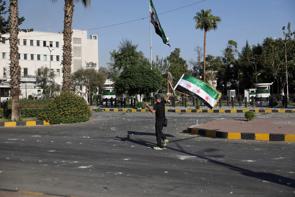 A man walks with a Syrian flag, after powerful airstrikes shook Damascus on Wednesday, targeting the defense ministry, as Israel vowed to destroy Syrian government forces attacking Druze communities in southern Syria and demanded their withdrawal, in Damascus July 16, 2025. REUTERS/Khalil Ashawi