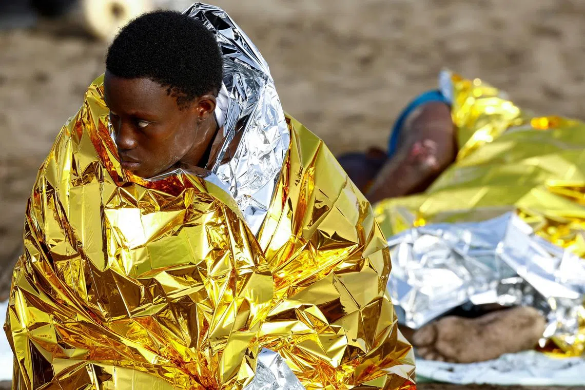 Two migrants rest on the sand after arriving in a fiber boat at Las Burras beach in San Agustin, on the island of Gran Canaria, Spain, July 19, 2024. REUTERS/Borja Suarez