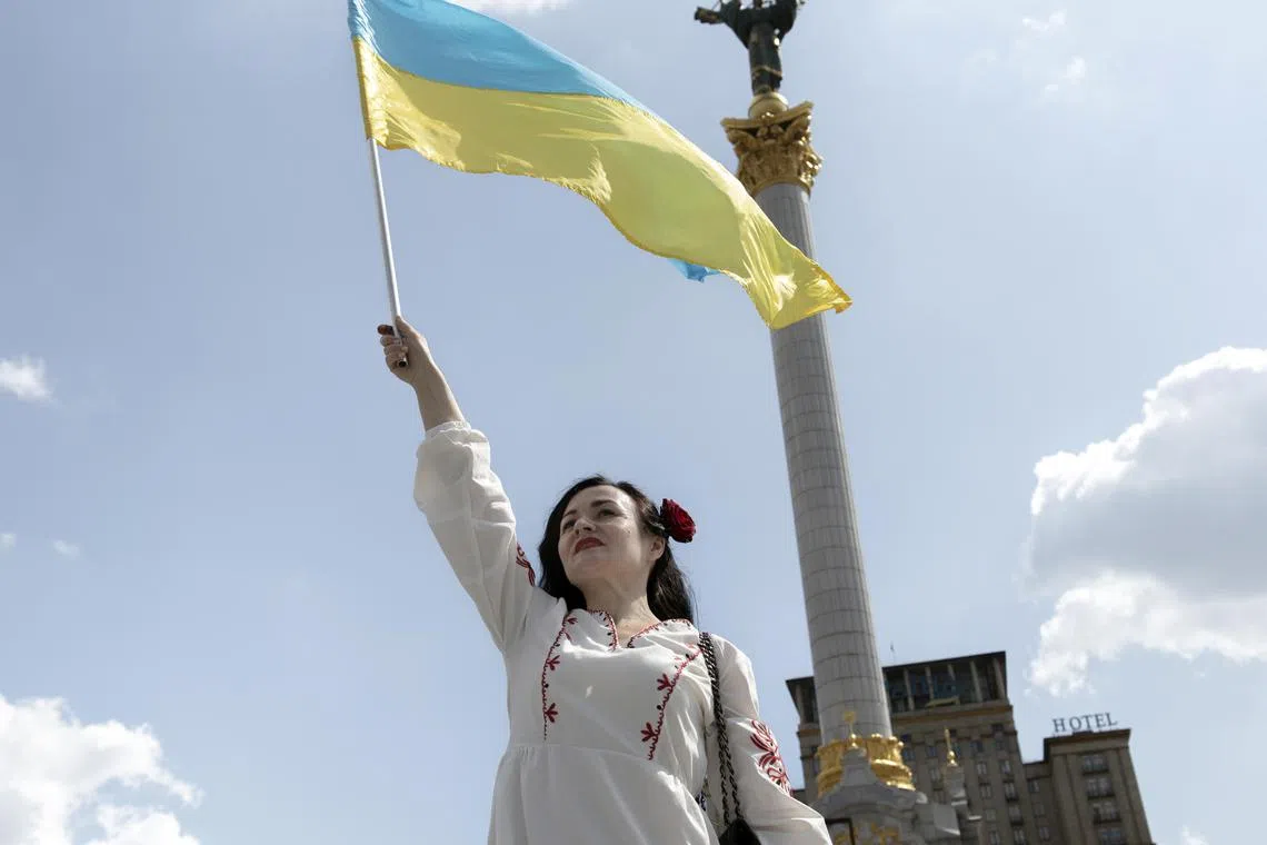 A woman waves the flag of Ukraine in Maidan Square in Kyiv on Ukraine's Independence Day. 