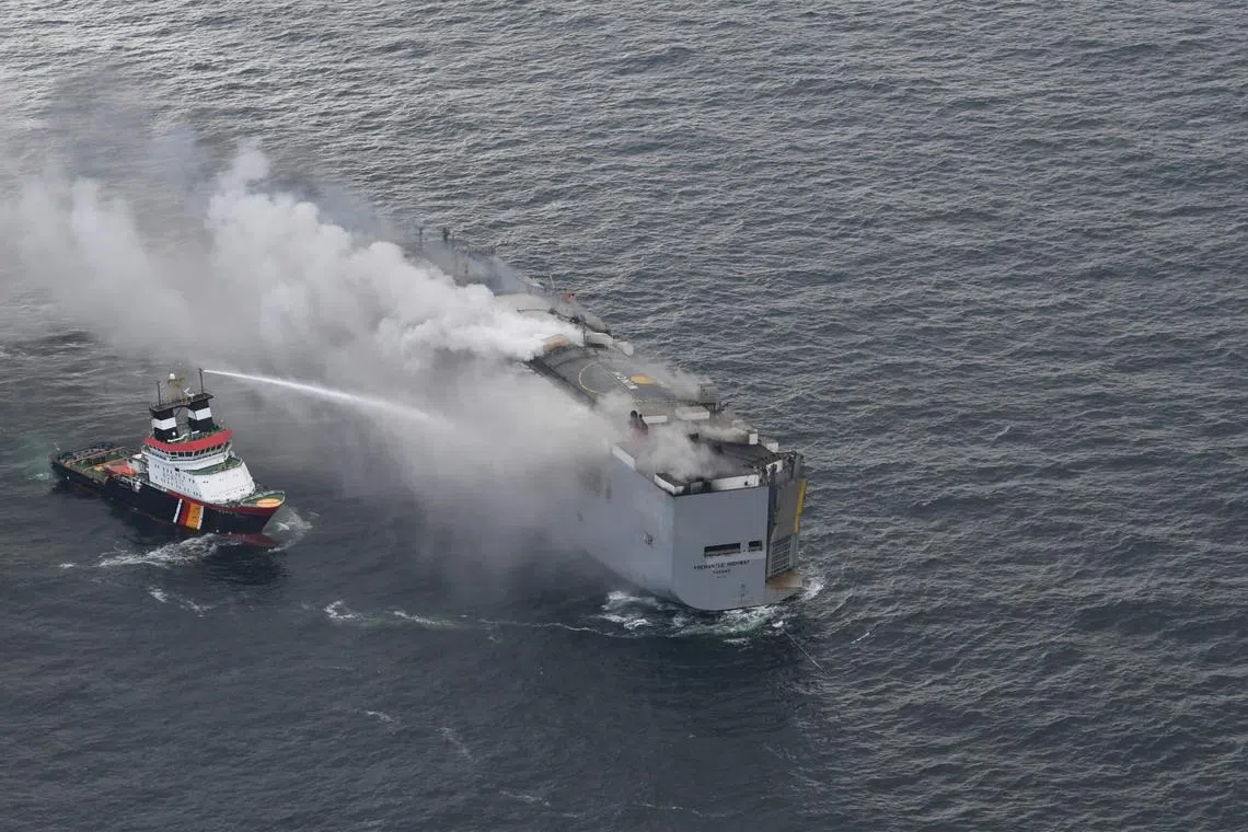 This handout photograph taken and released on July 26, 2023 by the Dutch coastguards, shows a fire aboard the Panamanian-registered car carrier ship Fremantle Highway, off the coast of the northern Dutch island of Ameland. Dutch firefighters battled for a second day, on July 27, 2023, to douse a blaze on a cargo ship off the Netherlands coast suspected to have been started by electric cars. 