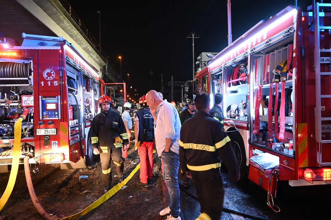 Firefighters work on the site of a bus accident on October 03, 2023 in Mestre, near Venice. At least 20 people were killed Tuesday when a bus plunged off a bridge in the northern Italian city of Venice, a city hall spokesman told AFP. The crash caused "at least 20 deaths, including two children," the spokesman said. Firefighters said the bus caught fire after careering off a bridge linking the Mestre and Marghera districts. (Photo by Marco SABADIN / AFP)