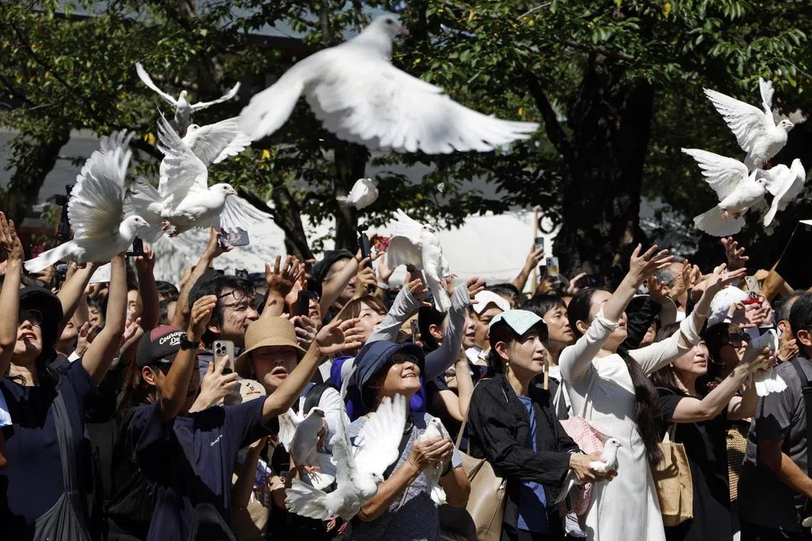 People releasing white doves at the Yasukuni Shrine in Tokyo as Japan marks the 80th anniversary of its surrender in World War II on Aug 15.