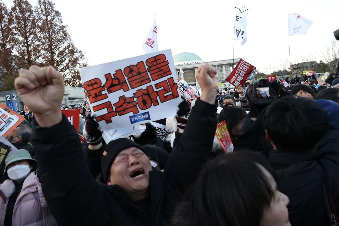 A demonstrator reacts after lawmakers passed a motion to impeach South Korean President Yoon Suk Yeol during a protest outside the National Assembly in Seoul, South Korea, on Saturday, Dec. 14, 2024. South Korean lawmakers impeached Yoon, putting him on the brink of being ousted less than two weeks after he shocked the nation by briefly imposing martial law. Photographer: Jean Chung/Bloomber