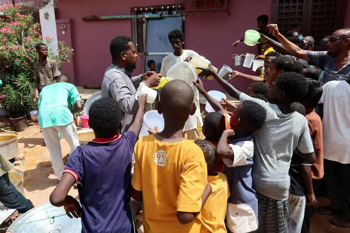 People hold pots as volunteers distribute food in Omdurman, Sudan, September 3, 2023. REUTERS/El Tayeb Siddig/ File Photo