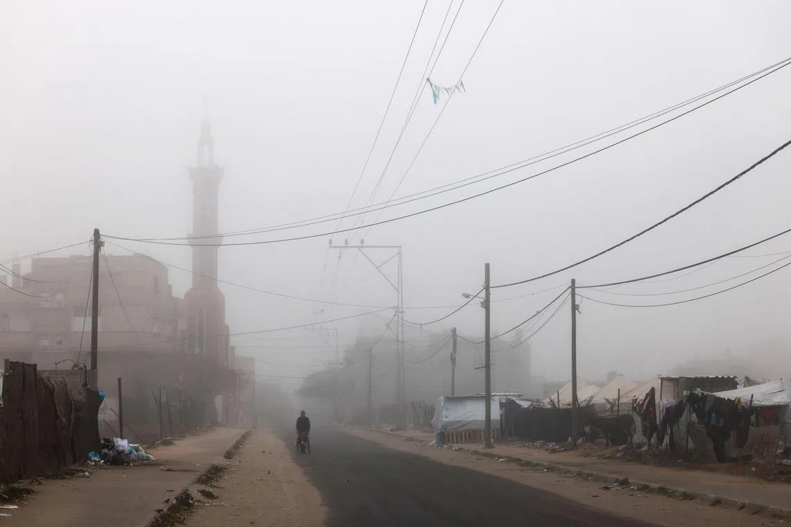 A Palestinian man pushing a baby in a stroller on a roadside amid thick fog in Rafah in the southern Gaza Strip in the early morning on April 4, 2024, amid the ongoing conflict between Israel and the militant group Hamas.