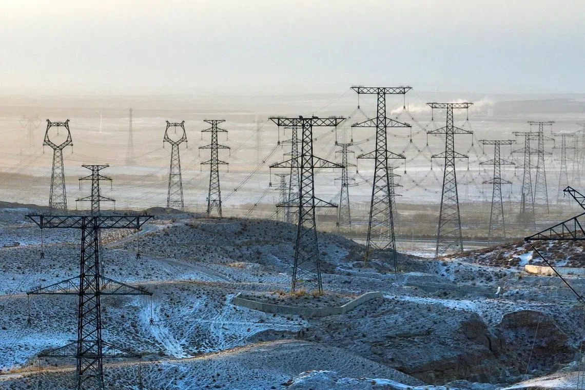 This aerial photo taken on January 21, 2024 shows electricity transmission towers in the snow-covered Gobi desert in Yinchuan, in China’s northern Ningxia region. (Photo by AFP) / China OUT