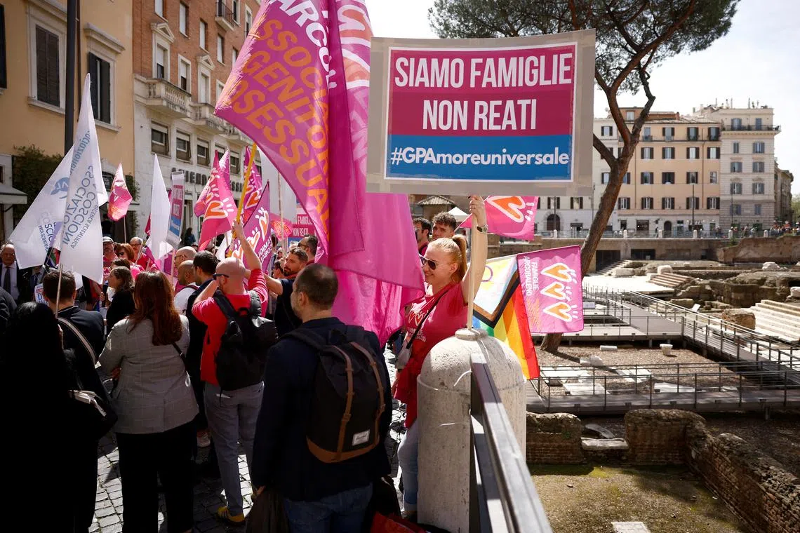 FILE PHOTO: A woman holds a banner during a demonstration in support of surrogate motherhood in Rome, Italy, April 5, 2024. Banner reads: \"We are families not crimes\". REUTERS/Guglielmo Mangiapane/File photo