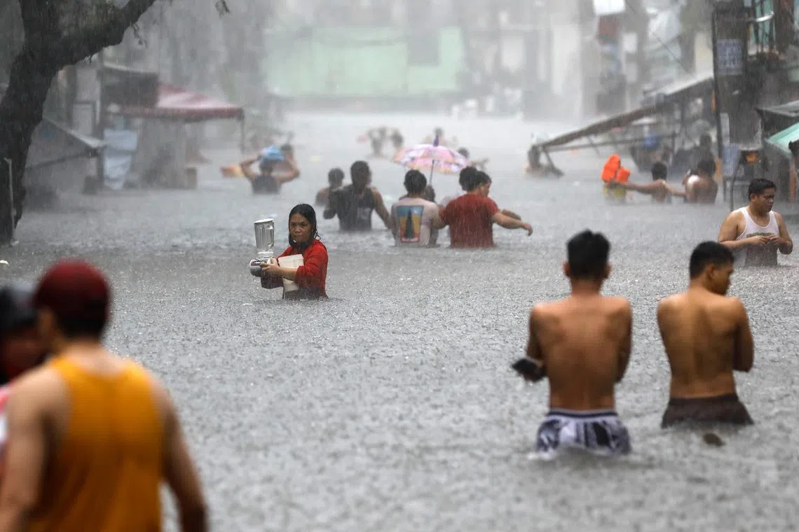Residents walking in a flooded area following monsoon rainfall caused by Typhoon Gaemi, in Quezon City, Manila, Philippines, on July 24, 2024. 