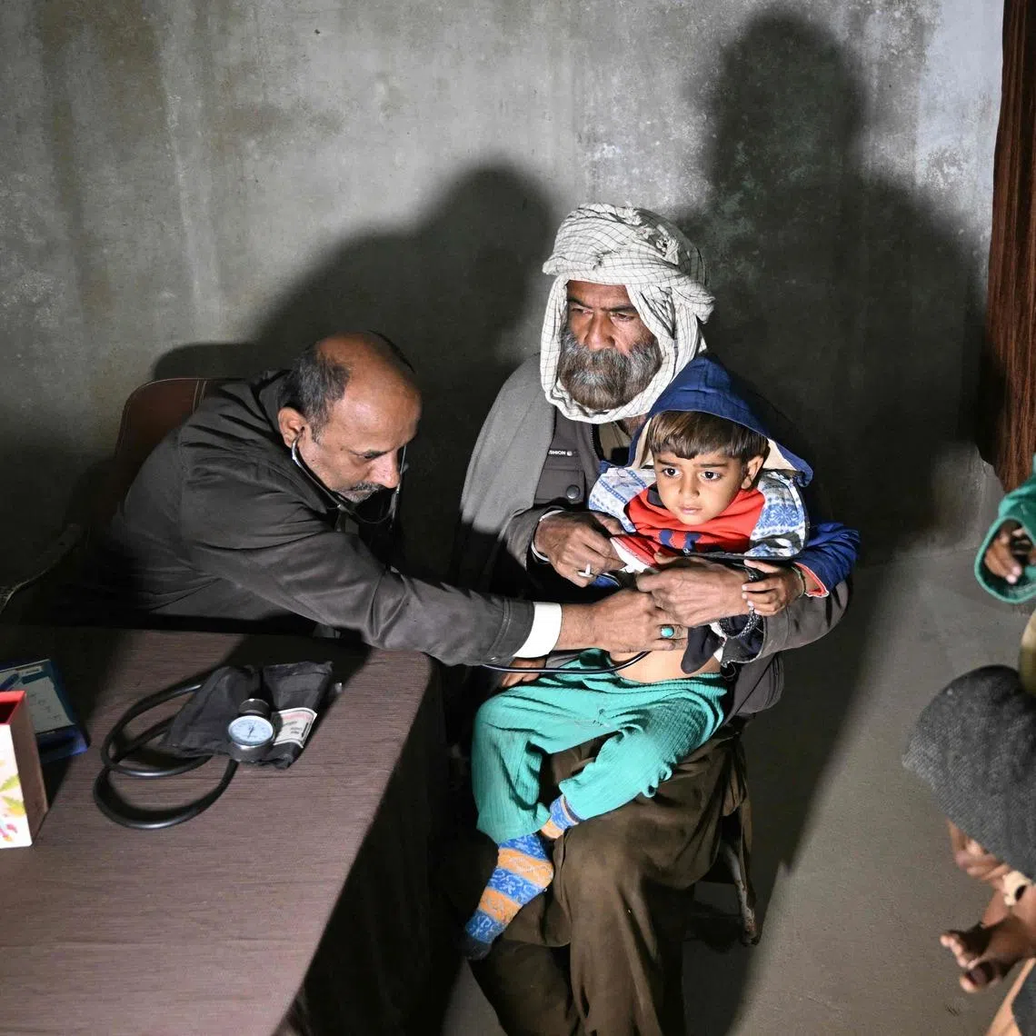 Mr Abdul Waheed (left) trying to diagnose a minor in his unlicensed clinic on the outskirts of Hyderabad city in Sindh province on Jan 8. Clinics like his are often the first point of care for poor communities.