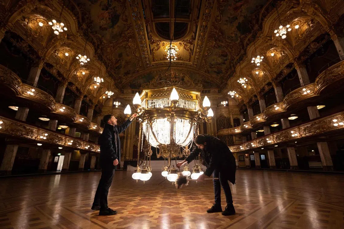 Josh Taylor (L) and Jordan Stimpson, members of the Tower Ballroom team, clean one of the 14 crystal Edwardian chandeliers that illuminate Blackpool Tower Ballroom, during its annual clean in Blackpool, northern England on January 16, 2023. - The Ballroom in Blackpool Tower is undergoing its annual spring clean which includes lowering the ornate chandeliers for one week to be cleaned ahead of the coming season of ballroom dancing. 