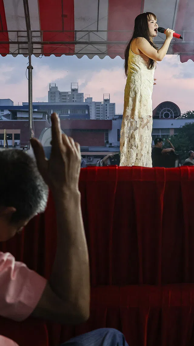 An elderly spectator waving to the tune of the Hokkien song sang by a getai singer at the hungry ghost festival getai show at Toa Payoh Industrial Park on Aug 20, 2026. ST PHOTO: BRIAN TEO