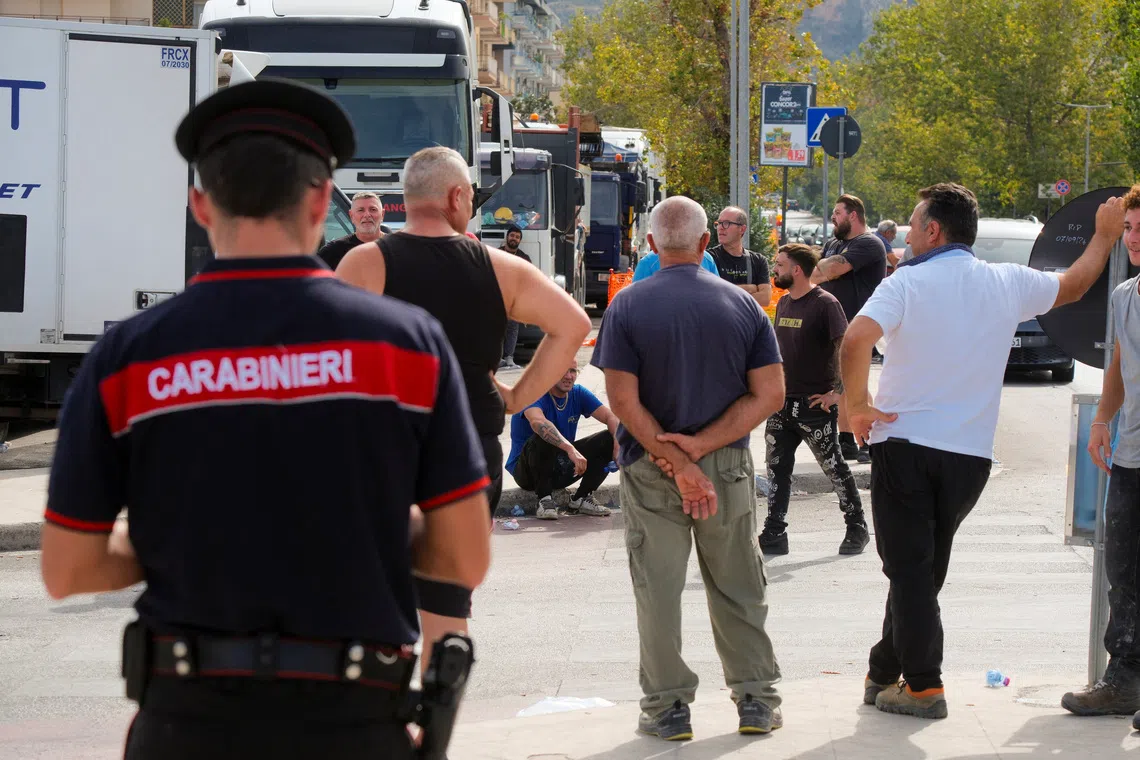 People gathering beside parked trucks during a protest by truckers over soaring fuel and transport costs, in Palermo, on Oct 20.