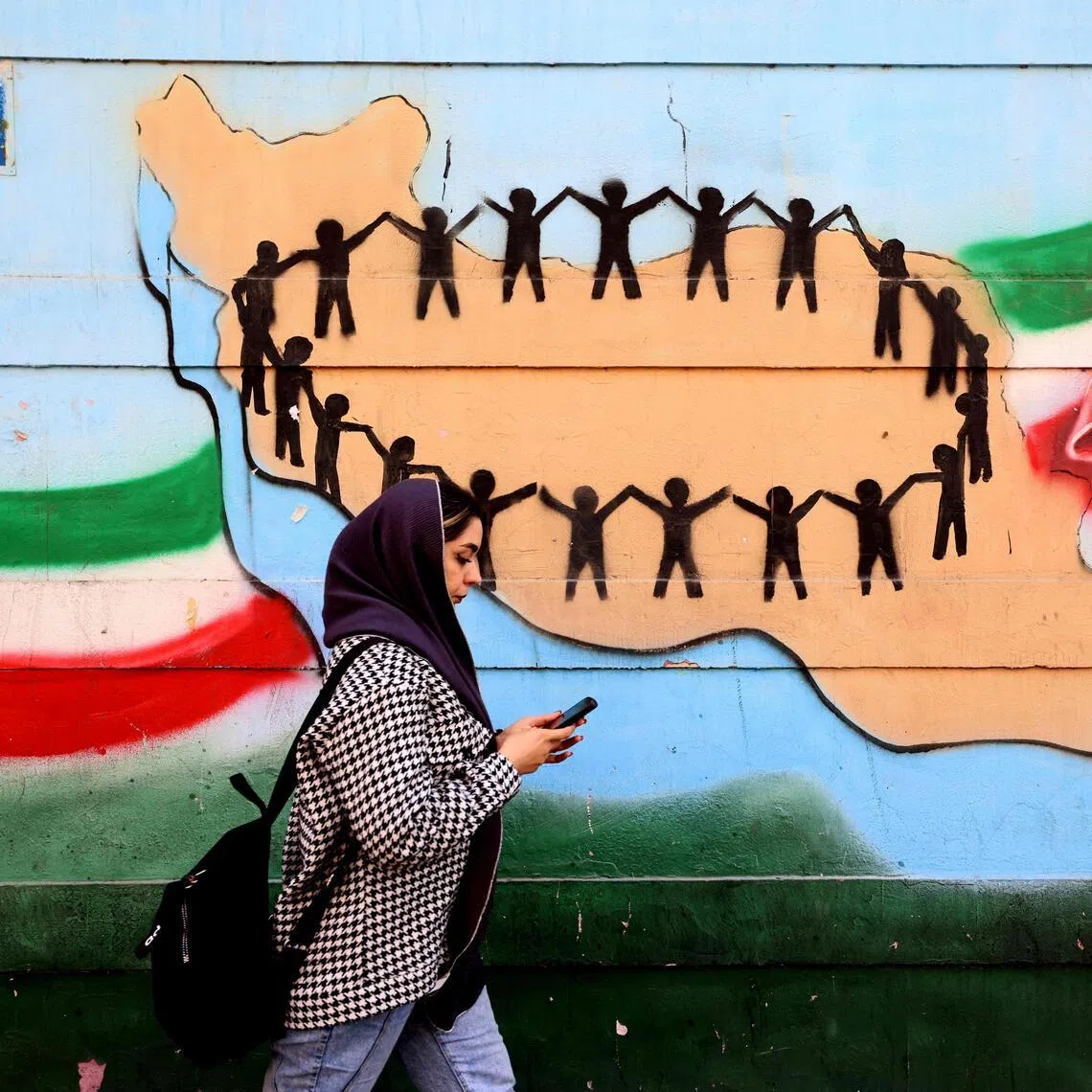 A woman walking past the flag and map of Iran painted on a wall in Tehran on Feb 25.