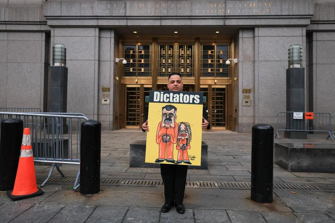 TOPSHOT - A demonstrator holds a sign featuring an illustration of ousted Venezuelan president Nicholas Maduro and his wife Cilia Flores, outside the Daniel Patrick Moynihan Federal Courthouse in New York City on July 22, 2026. Venezuela's ousted president Nicolas Maduro is set to appear in federal court Wednesday, his third public hearing since the US military captured him in a stunning nighttime raid in January. The former leader, 63, and wife Cilia Flores have been held in a Brooklyn jail since the US military operation, awaiting trial on drug trafficking, firearms and other charges. (Photo by TIMOTHY A. CLARY / AFP)