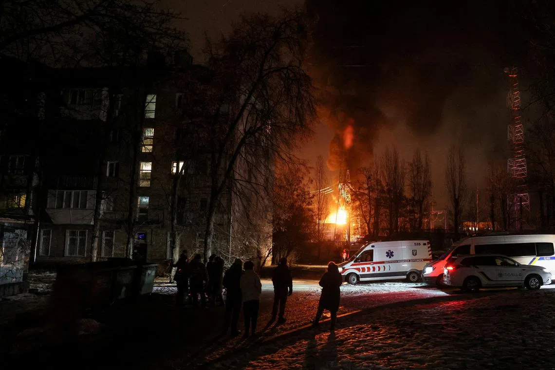 Local residents gather near a residential building as a critical power infrastructure object burns after a Russian drone attack in Kyiv, Ukraine, on Dec 19, 2022.