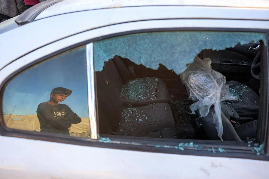 TOPSHOT - People inspect a damaged vehicle at the site of reported Israeli bombardment on tents sheltering Palestinians displaced from Beit Lahia at a camp in Khan Yunis in the southern Gaza Strip on December 25, 2024 amid the ongoing war in the Palestinian territory between Israel and Hamas. (Photo by BASHAR TALEB / AFP)