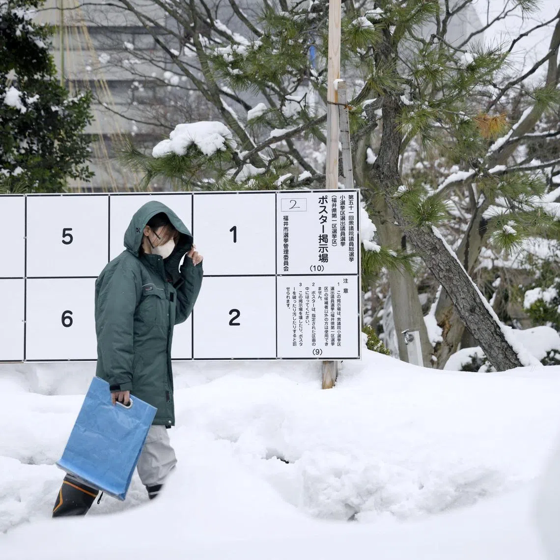 A person walks past a bulletin board for posters of candidates for the February 8 snap election, where snow has accumulated, in Fukui, Japan, January 26, 2026, in this photo taken by Kyodo. Mandatory credit Kyodo/via REUTERS