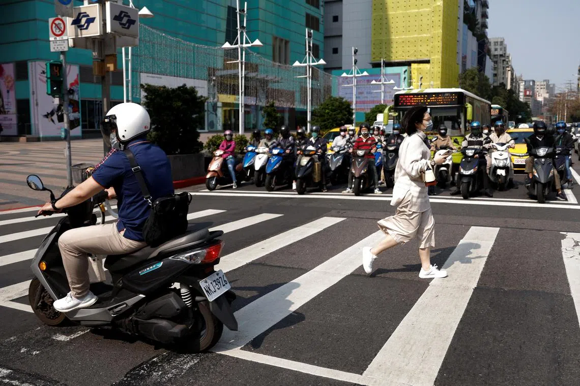 A woman crosses a street during morning rush hour in Taipei, Taiwan April 11, 2023. REUTERS/Carlos Garcia Rawlins
