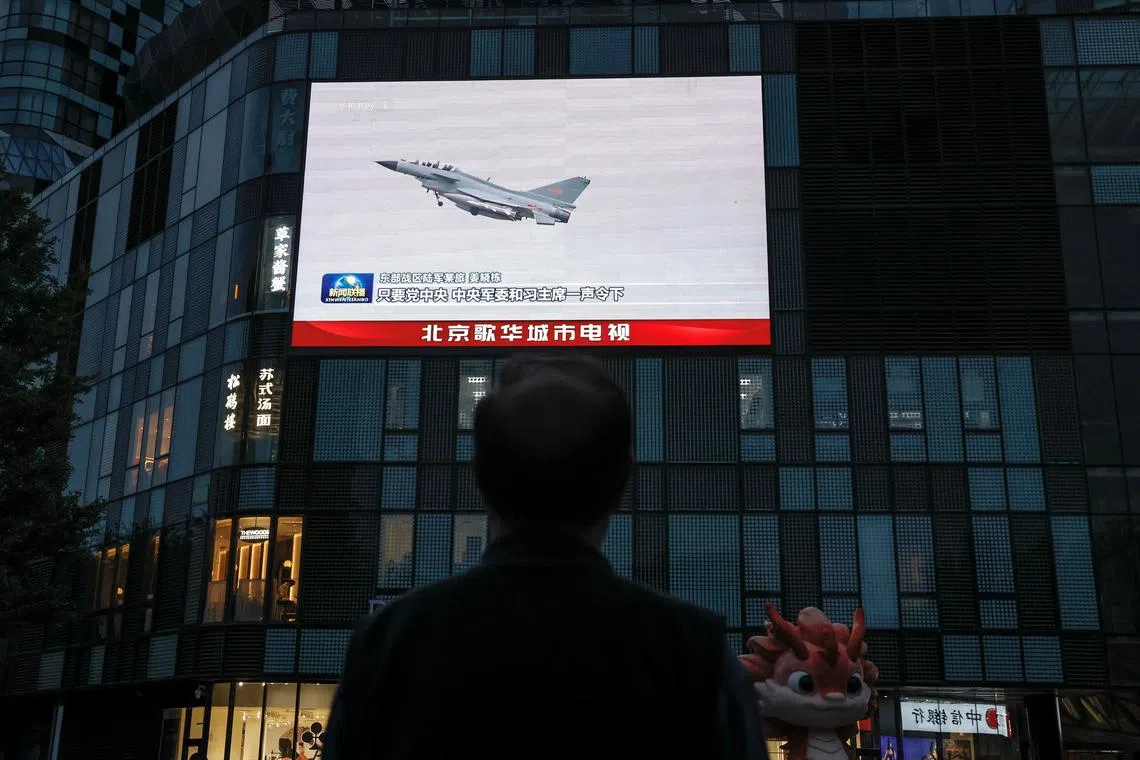 FILE PHOTO: A man looks at a giant screen showing news footage of military drills conducted in areas around the island of Taiwan by the Eastern Theatre Command of the Chinese People's Liberation Army (PLA), in Beijing, China May 24, 2024. REUTERS/Tingshu Wang/File Photo