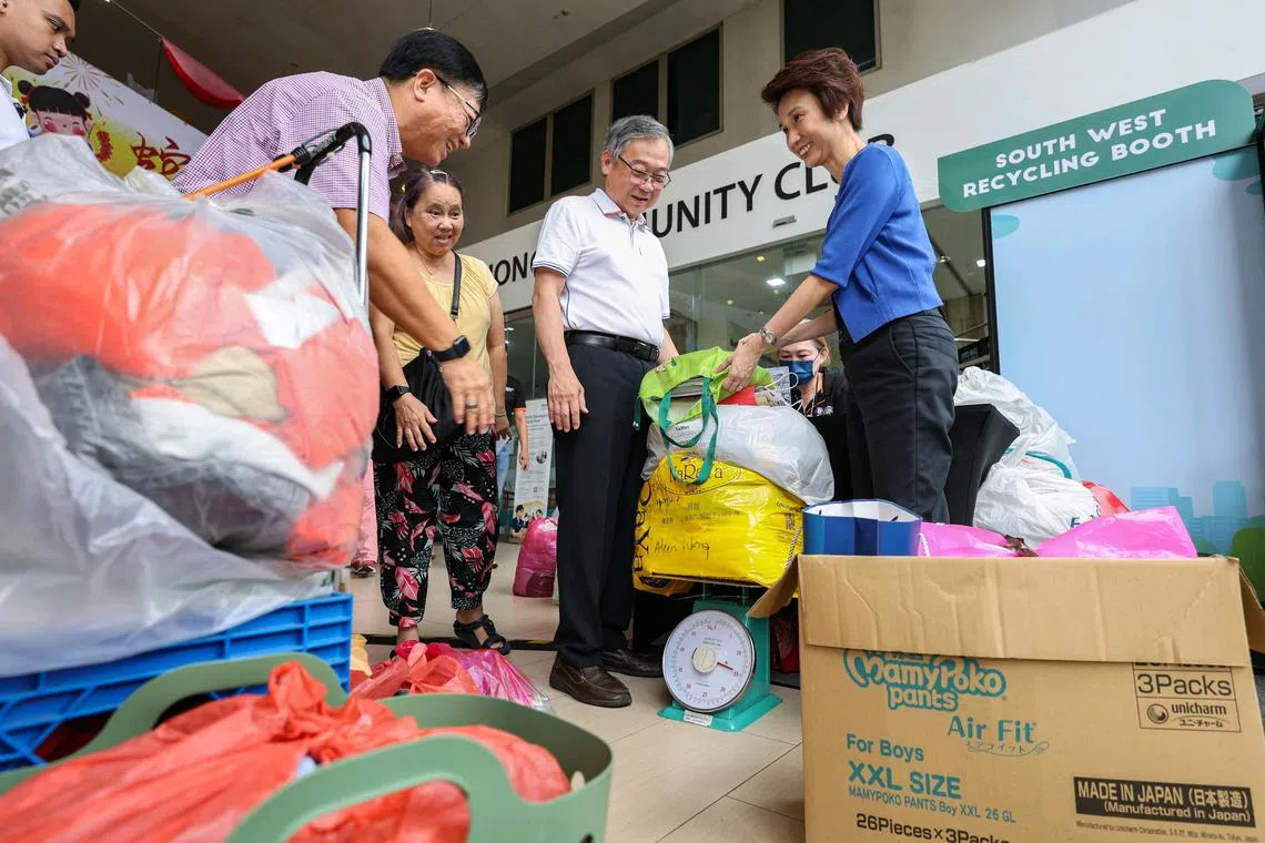 ST20250125_202570400439/jlclean/Brian Teo/Joyce Lim BH/(From Left) Deputy Prime Minister Gan Kim Yong and Senior Minister of State for Ministry of Culture, Community and Youth and Ministry of Trade and Industry Low Yen Ling helping Madam Wee Wot Yeen (in yellow), 65, weigh the 15.5kg of old clothes and newspapers that she brought to the South West Recycling booth during the Clean Up @ South West 2025 event at Keat Hong community centre on Jan 25, 2025. ST PHOTO: BRIAN TEO