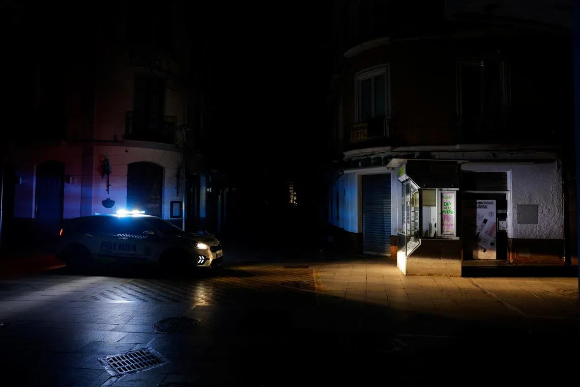 A local police car patrols a shopping street without electric lighting to prevent theft and looting in the stores in the early morning hours during a power outage which hit large parts of Spain, in Ronda, Spain April 29, 2025. REUTERS/Jon Nazca