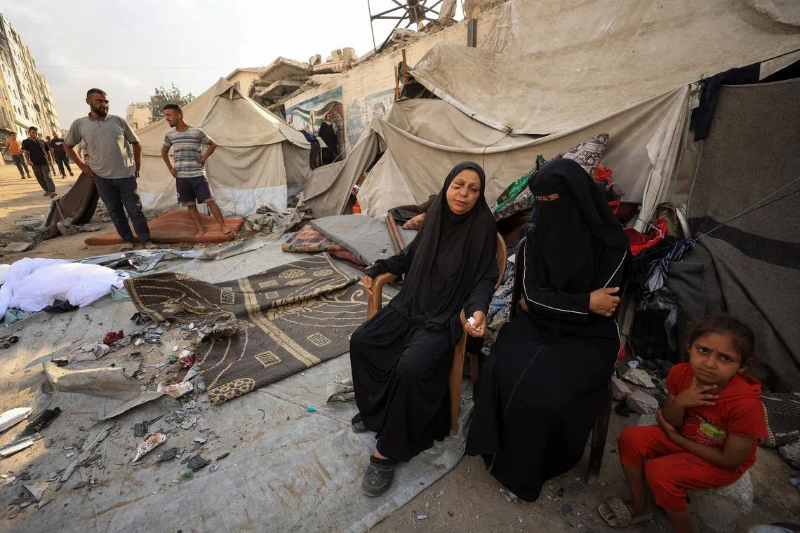 FILE PHOTO: Palestinians women and a girl sit while others inspect the site of an overnight Israeli strike on a tent, in Gaza City, September 7, 2025. REUTERS/Dawoud Abu Alkas/ File Photo