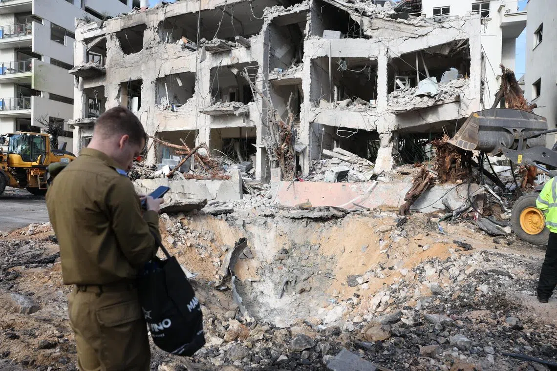 Emergency services personnel inspect the damage at the scene of a building that was struck by an Iranian missile in Tel Aviv, Israel.