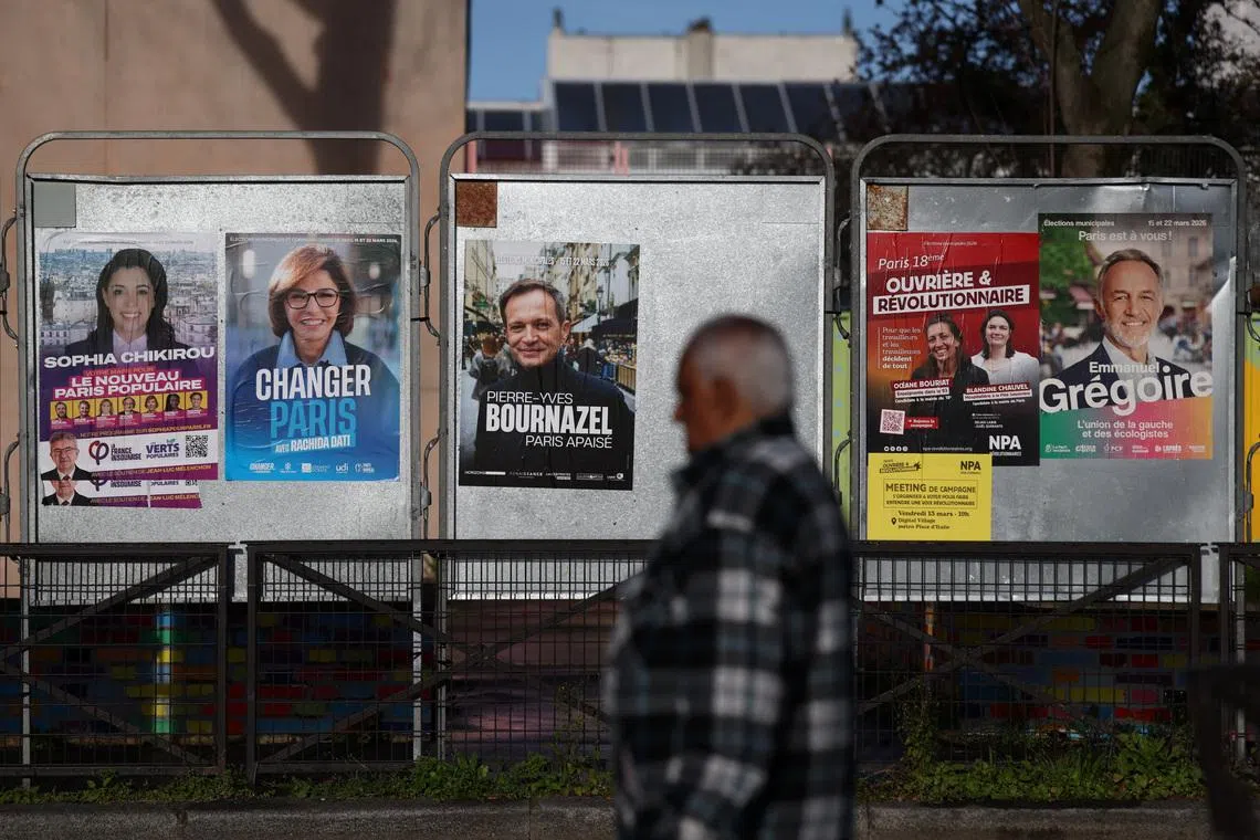 A man walks past election posters on the day of the first round of the French mayoral election, in Paris, France, March 15, 2026. REUTERS/Tom Nicholson