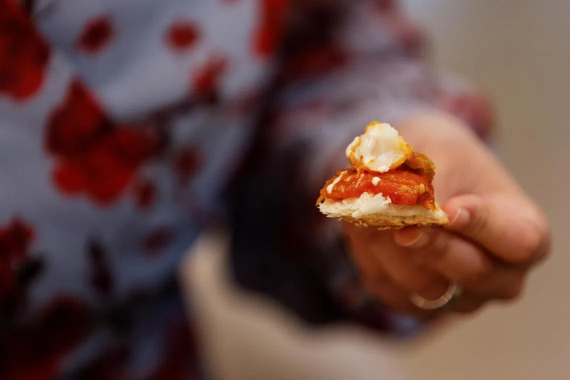 The representative director of Japan Association for Cellular Agriculture holds up a morsel of a dish containing 3D-printed cultivated grouper fish during a tasting at the offices of Steakholder Foods in Rehovot, Israel, April 23, 2023. REUTERS/Amir Cohen