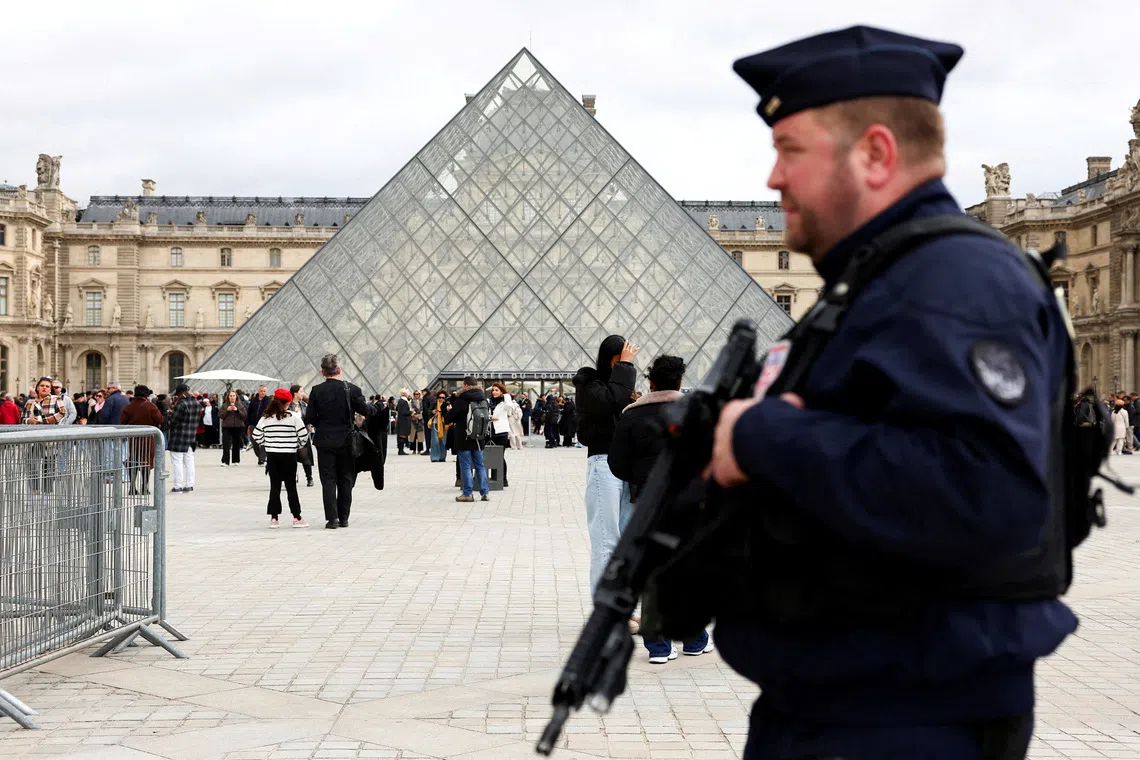 FILE PHOTO: A French CRS riot police officer patrols near the glass Pyramid of the Louvre Museum, after French police arrested suspects in the Louvre heist case, in Paris, France October 27, 2025. REUTERS/Abdul Saboor/File Photo