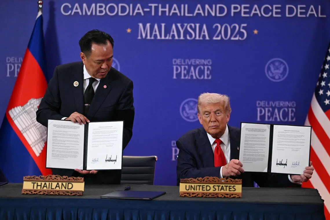 US President Donald Trump holds up a signed document with Thailand's Prime Minister Anutin Charnvirakul during the signing of a ceasefire agreement between Cambodia and Thailand in Kuala Lumpur on Oct 26, 2025.