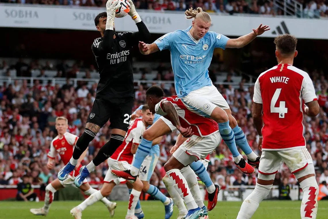 Arsenal goalkeeper David Raya catching the ball under pressure from Manchester City striker Erling Haaland during the English Premier League match at The Emirates stadium.