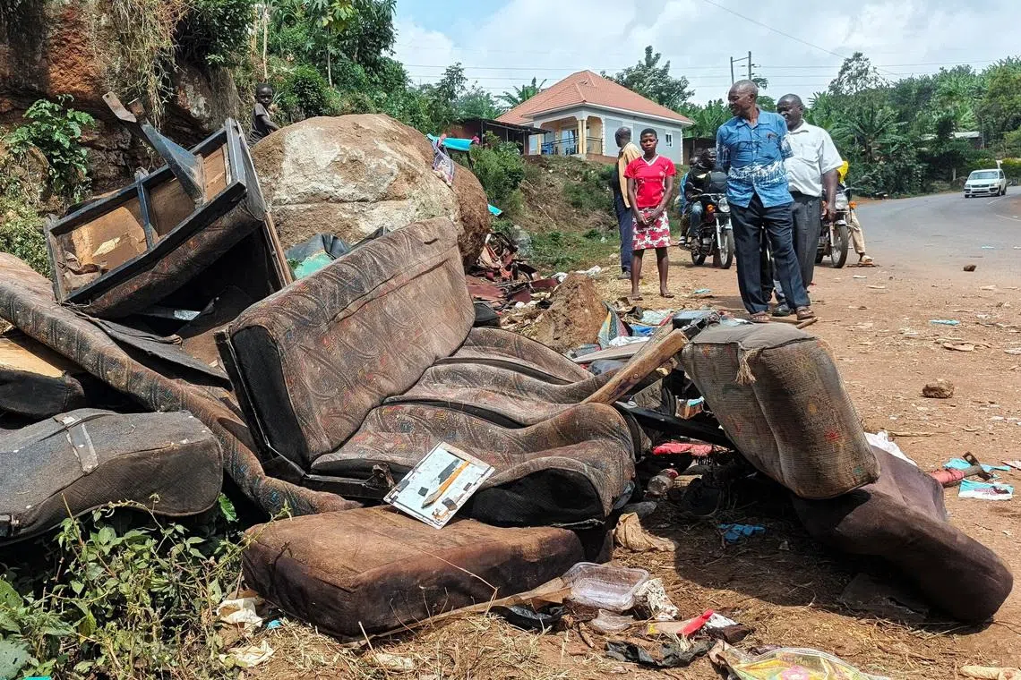 People walk near the wreckage of a bus, owned by King David Junior School, on the shoulder of the road following an accident that killed schoolchildren on the way back from an educational visit to Sipi Falls, at Chekwatit village in Kapchorwa district, Uganda, July 17, 2026. Picture taken with a mobile phone. REUTERS/Stringer