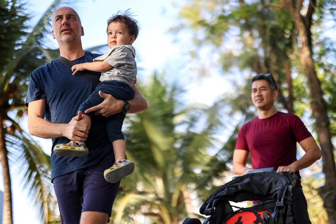 A gay couple, Jacob Holder, 45, holds up his son, Elijah Bprin Holder Koonpaew, while walking with  Surapong \"Keng\" Koonpaew, at a park in Bangkok, Thailand, January 11, 2025. REUTERS/Athit Perawongmetha