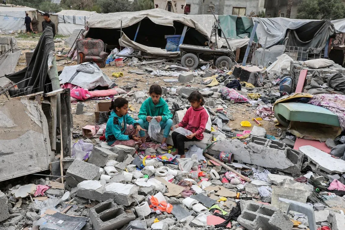 Young Palestinians sitting amid rubble at the site of an Israeli strike on a house, in Deir Al-Balah in the central Gaza Strip on April 8, 2025. 