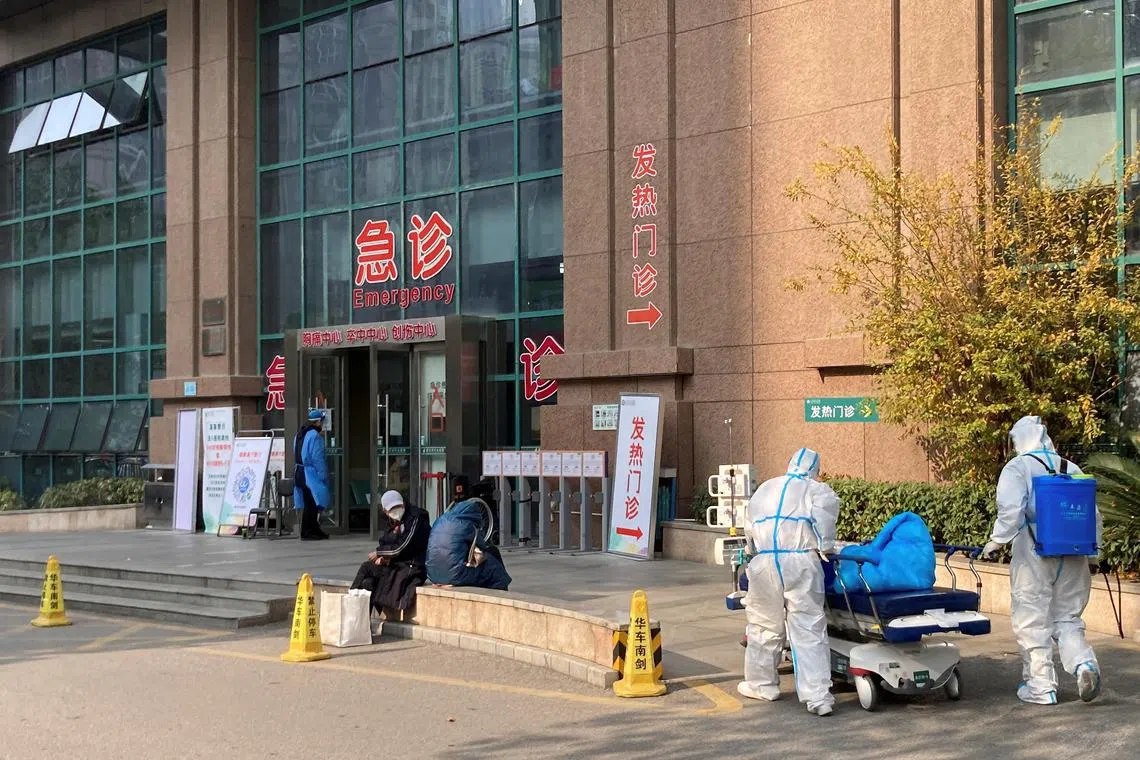 Workers in protective suits push a hospital bed outside The Central Hospital of Wuhan, after the government gradually loosened coronavirus disease (COVID-19) restrictions, in Wuhan, Hubei province, China December 9, 2022. REUTERS/Martin Pollard