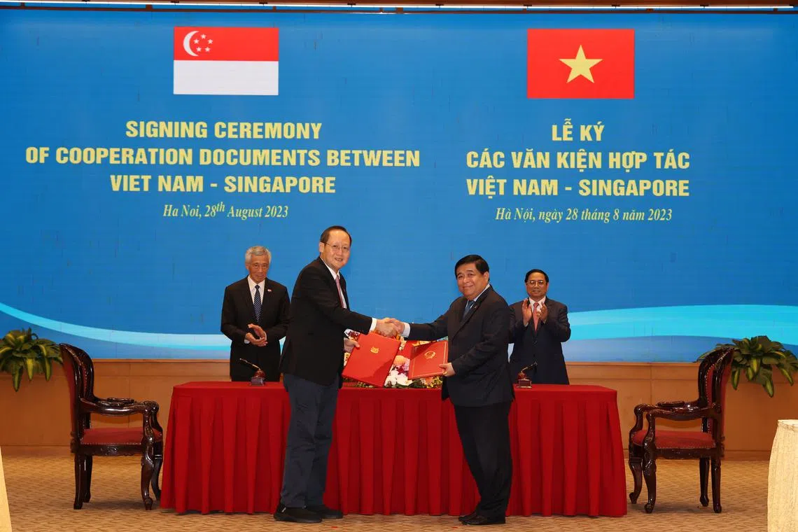 PM Lee Hsien Loong (in background, left) and Vietnam's PM Pham Minh Chinh (in background, right) witnessing the exchange of letters by Second Minister for Trade and Industry Tan See Leng and Vietnam’s Planning and Investment Minister Nguyen Chi Dzung on Aug 28.
