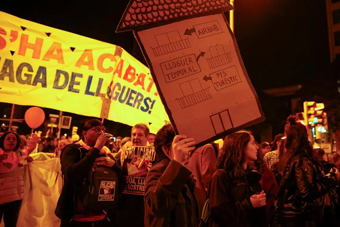 FILE PHOTO: A demonstrator holds a house-shaped sign that reads \"from touristic flat to temporary rent to Airbnb\" during a protest to demand lower housing rental prices and better living conditions, in Barcelona, Spain, November 23, 2024. REUTERS/Bruna Casas/File Photo