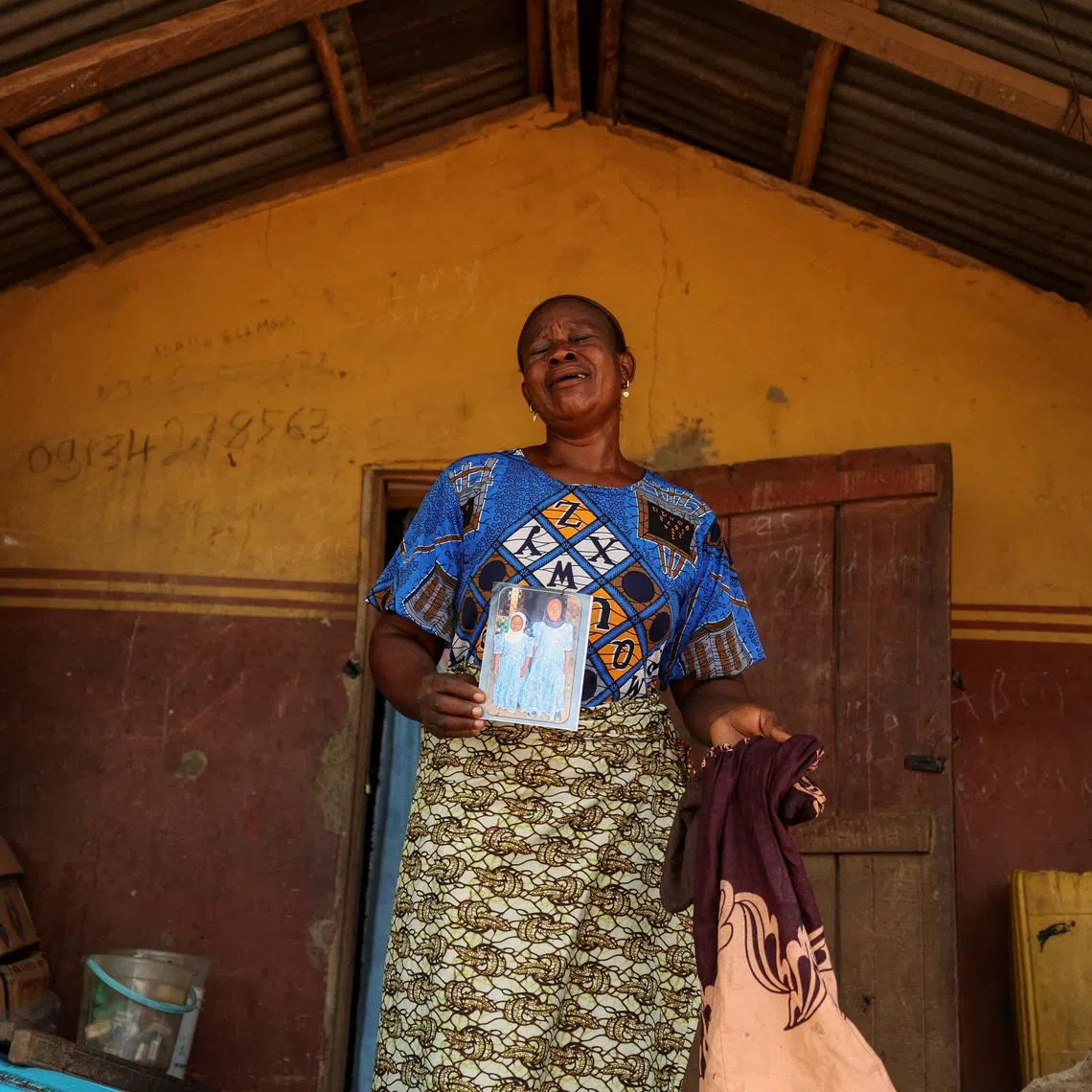 Aduke Balogun, whose daughter was among dozens of pupils and teachers abducted in a large-scale school attack in southwestern Nigeria, reacts while displaying her daughter's photograph and clothing after an interview with Reuters at her home in Yawota, Oyo State, Nigeria, June 2, 2026. REUTERS/Sodiq Adelakun
