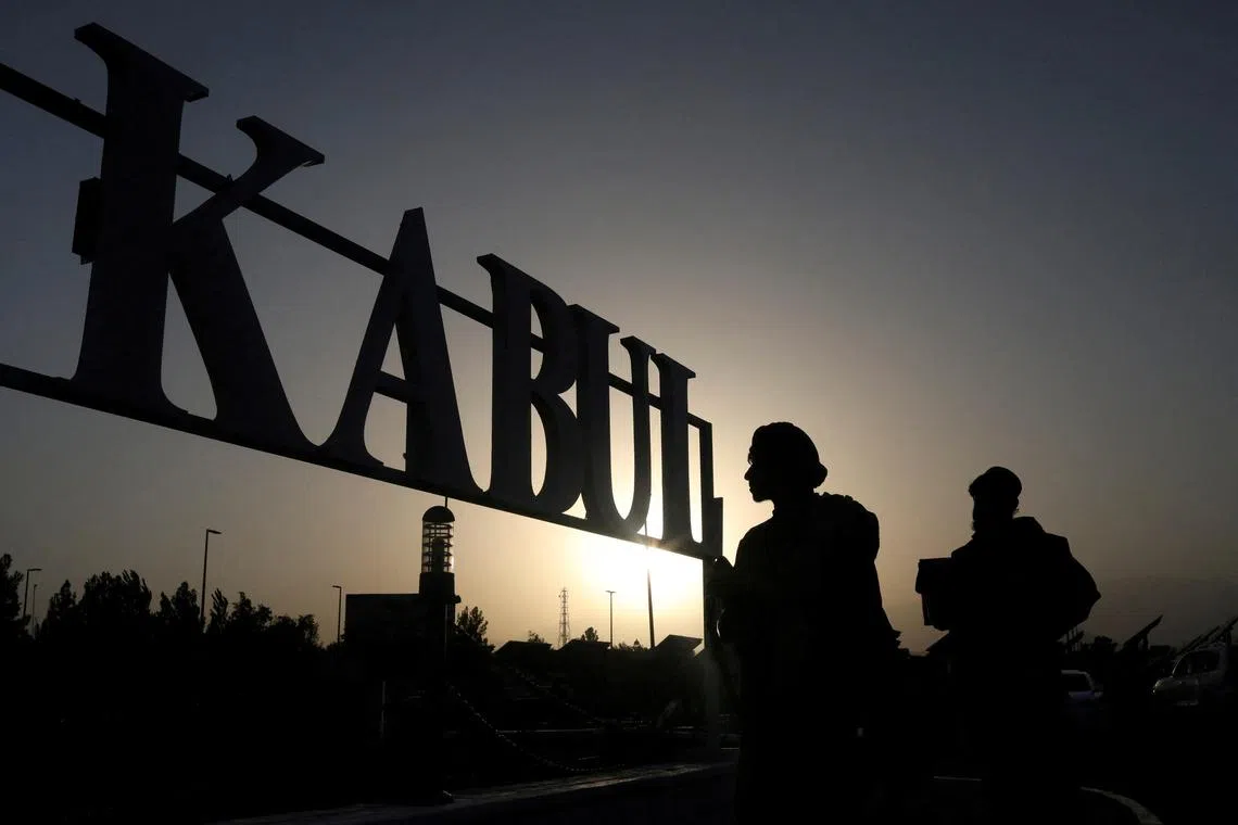 FILE PHOTO: Taliban soldiers stand in front of a sign at the international airport in Kabul, Afghanistan, September 9, 2021. WANA (West Asia News Agency) via REUTER/File Photo