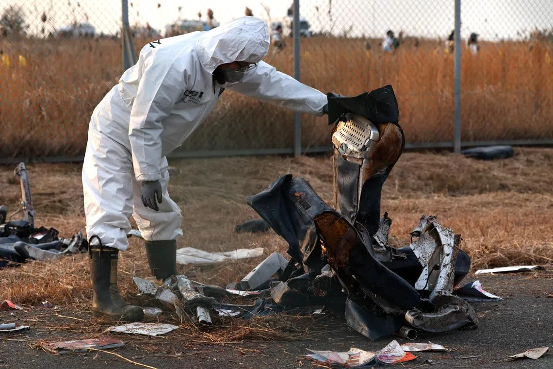 epa11796990 A member of Korea Crime Scene Investigation (KCSI) inspects the wreckage of the Jeju Air aircraft at Muan International Airport in Muan, 288 kilometers southwest of Seoul, South Korea, 29 December 2024. According to the National Fire Agency, a passenger jet carrying 181 people erupted in flames after going off the runway at an airport in South Korea's southwestern county of Muan on 29 December, leaving at least 62 people dead.  EPA-EFE/HAN MYUNG-GU