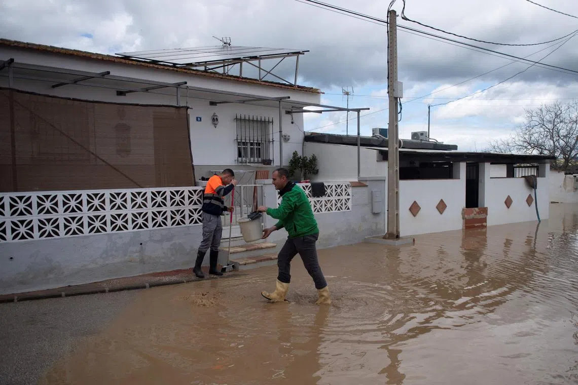 Residents clean a street flooded in Cartama, near Malaga, southern Spain, on March 18.