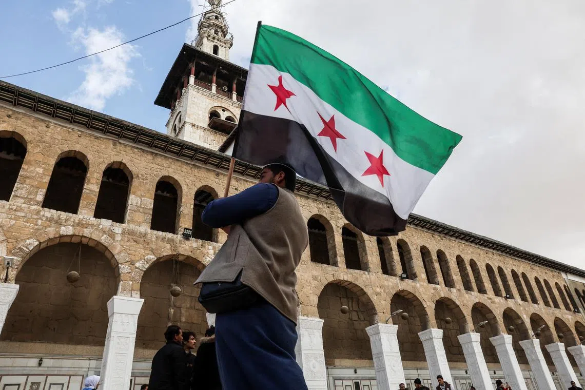 FILE PHOTO: A person carries a flag adopted by the new Syrian rulers, in the Umayyad Mosque, after Syria's Bashar al-Assad was ousted, in Damascus, Syria, December 27, 2024. REUTERS/Amr Abdallah Dalsh/File Photo