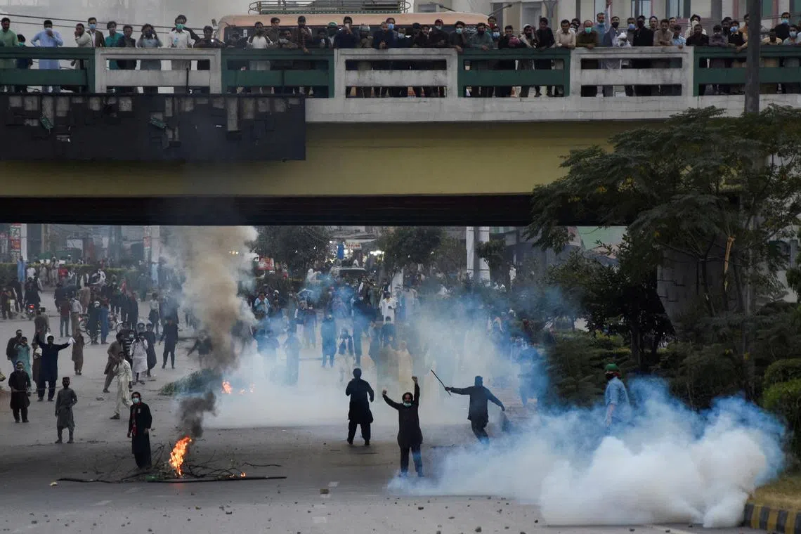  People reacting as police use tear gas to disperse them during a protest to condemn the shooting incident on a long march held by Pakistan's former Prime Minister Imran Khan in Wazirabad, in Rawalpindi, Pakistan, on Friday. Supporters of Mr Khan staged fresh protests on Tuesday. 