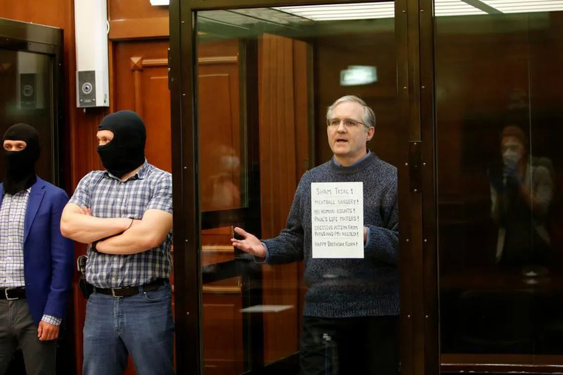 Former U.S. Marine Paul Whelan, who was detained and accused of espionage, holds a sign as he stands inside a defendants' cage during his verdict hearing in Moscow, Russia June 15, 2020. REUTERS/Maxim Shemetov/File Photo